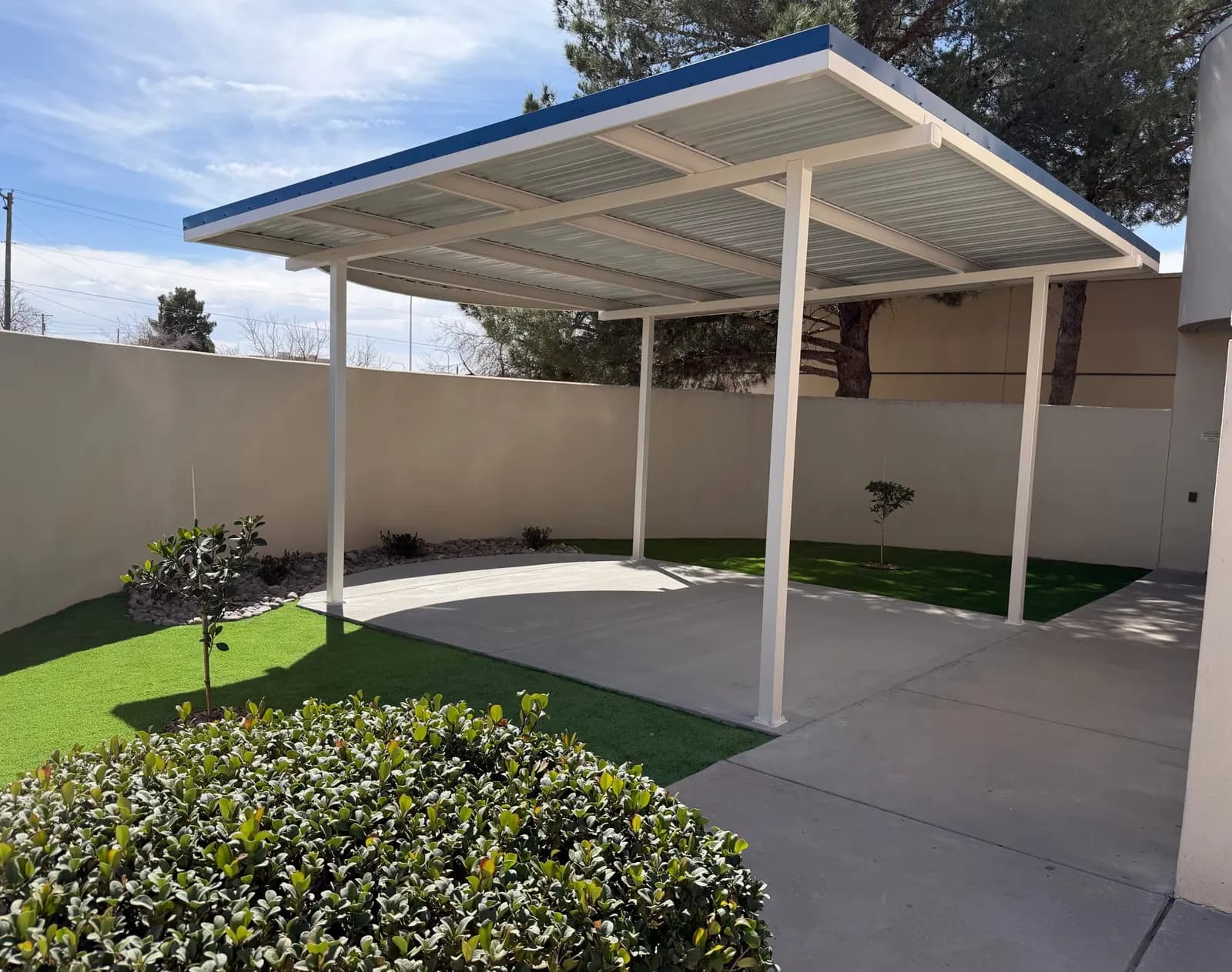 Steel shade canopy on white posts shading a concrete patio in a walled courtyard, Las Cruces